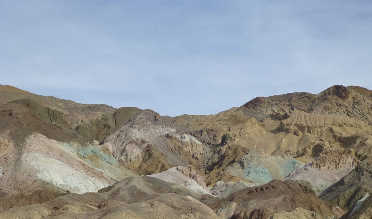 A mountain range radiates sunlight in a variety of sedimentary colors.