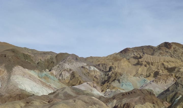 A mountain range radiates sunlight in a variety of sedimentary colors.